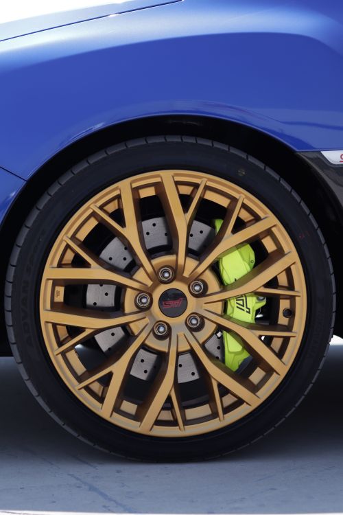 Free Detailed shot of a gold alloy wheel on a blue sports car featuring yellow brake calipers. Stock Photo
