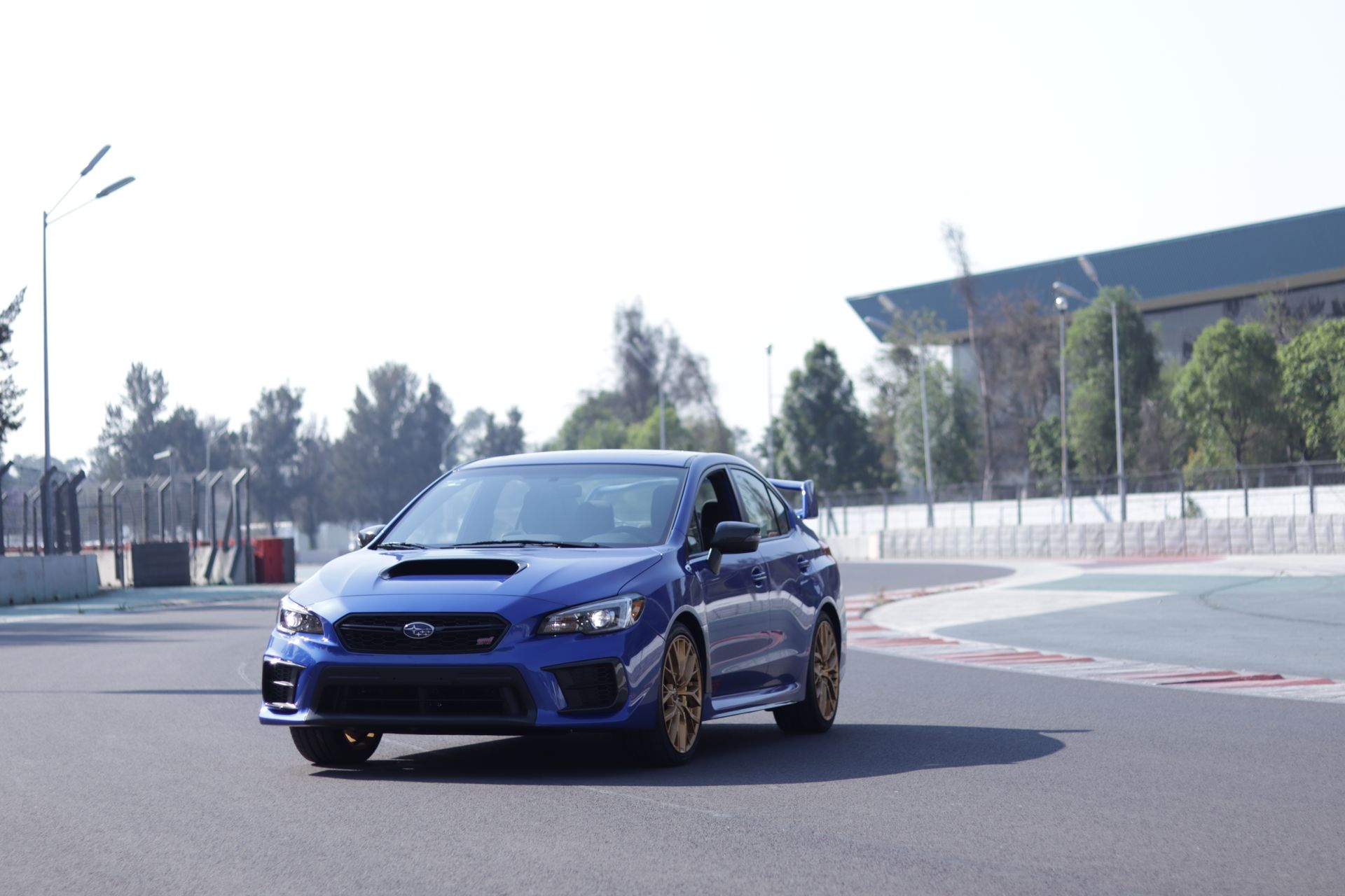 Dynamic shot of a blue Subaru racing car on an asphalt track during the day.