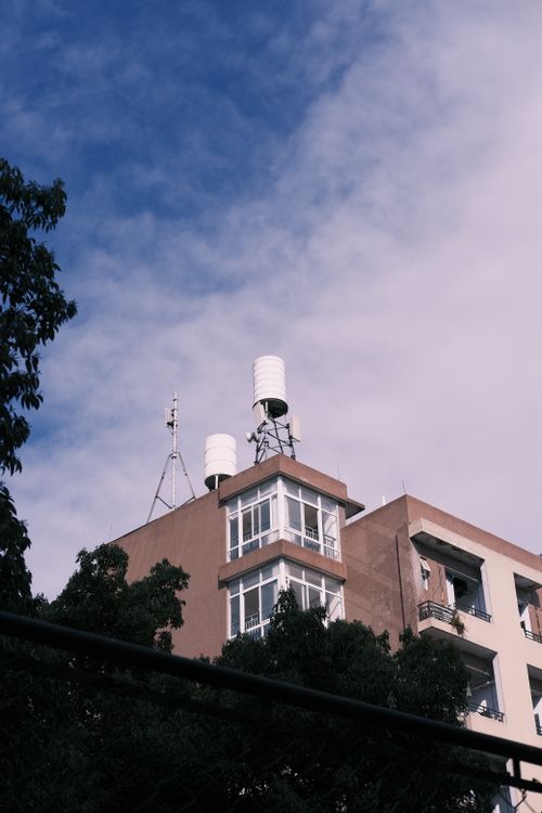 Free Low angle view of a modern residential building with water tanks and antennas under a clear blue sky. Stock Photo