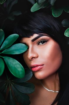 Close-up portrait of a woman framed by lush green leaves, highlighting natural beauty.