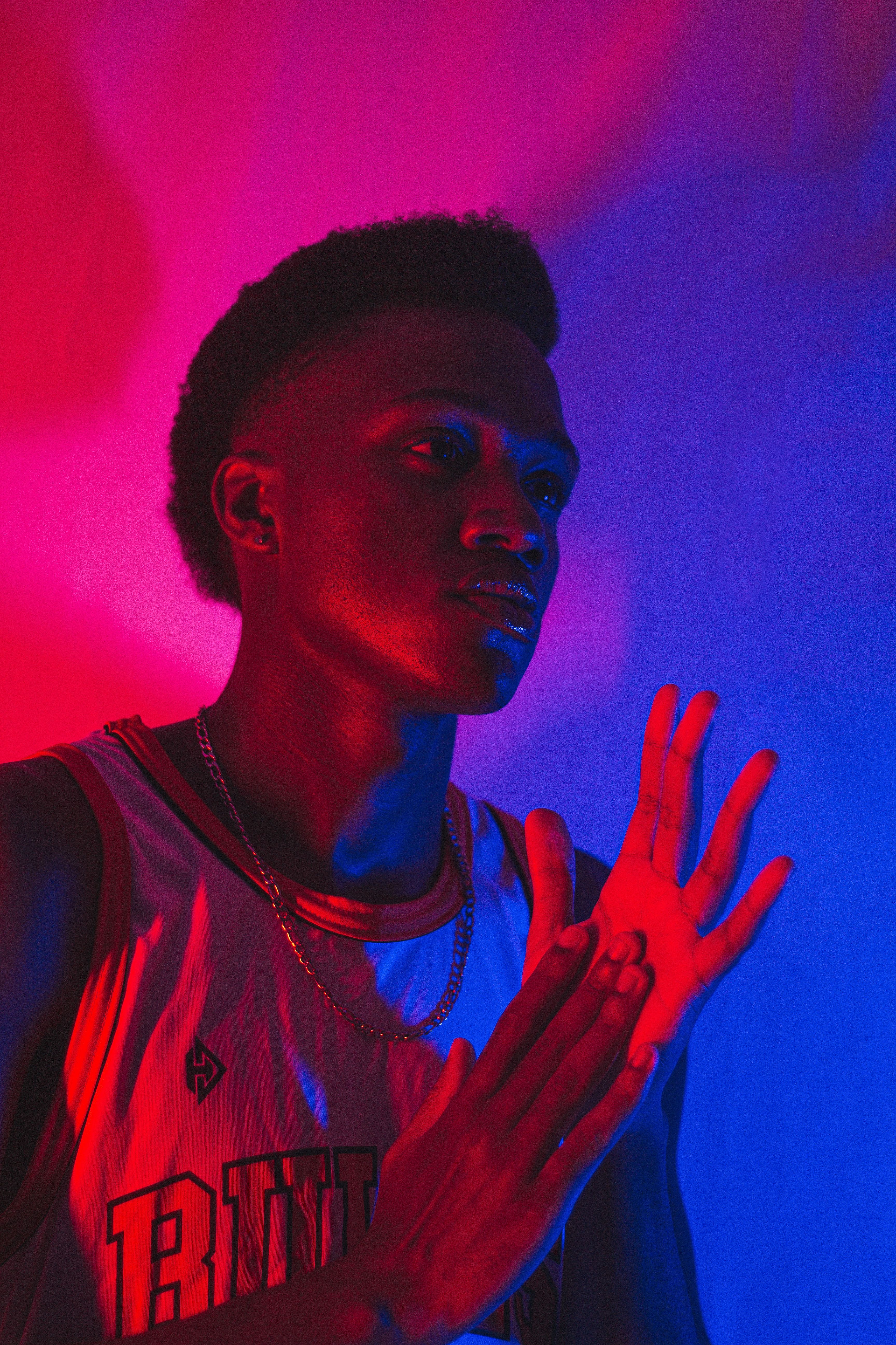 Stylish portrait of a man in studio with dynamic red and blue lighting.