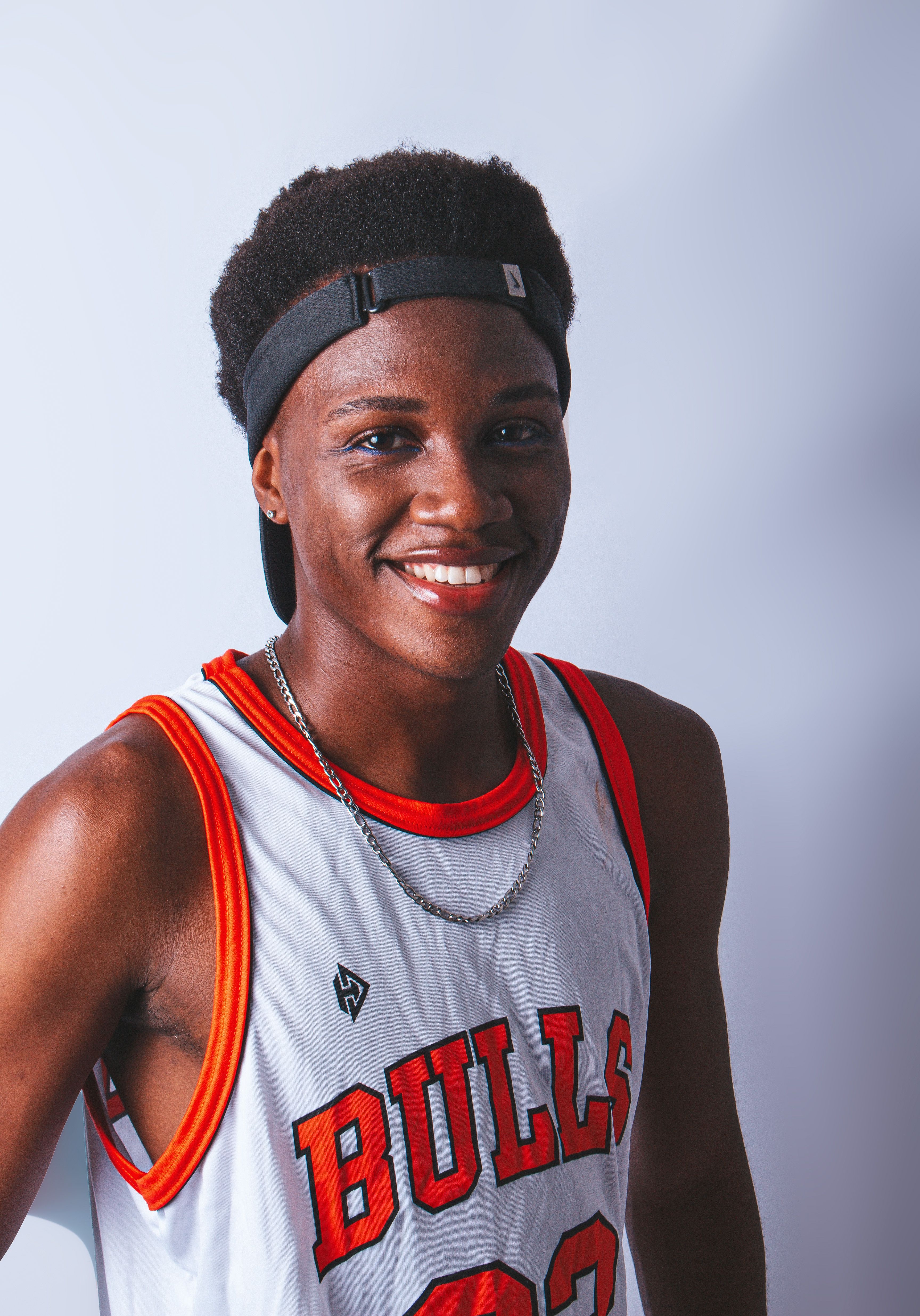 Portrait of a smiling teenager wearing a Bulls basketball jersey and headband.