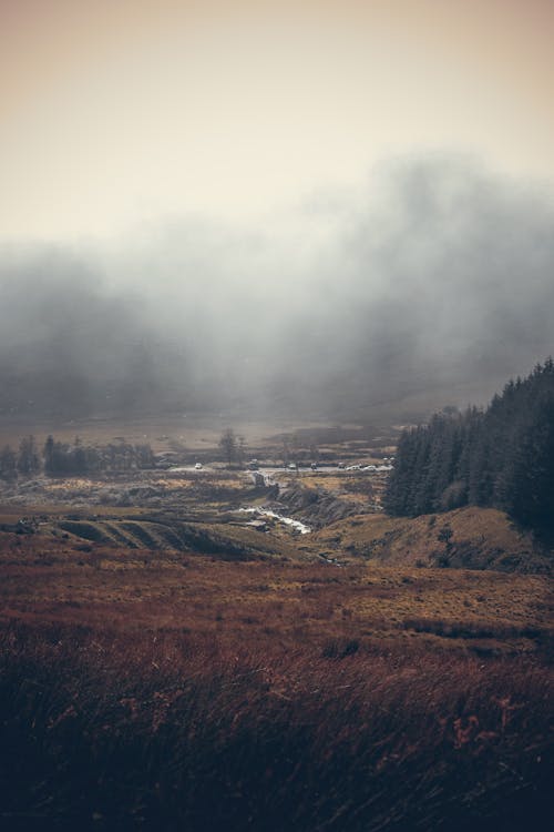 A foggy landscape with a river and a small town