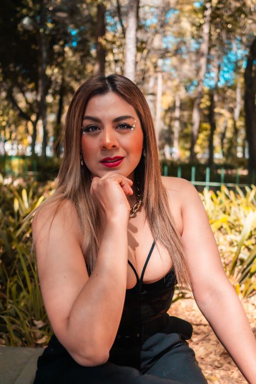 Free Portrait of a fashionable woman relaxing outdoors in a sunlit city park. Stock Photo