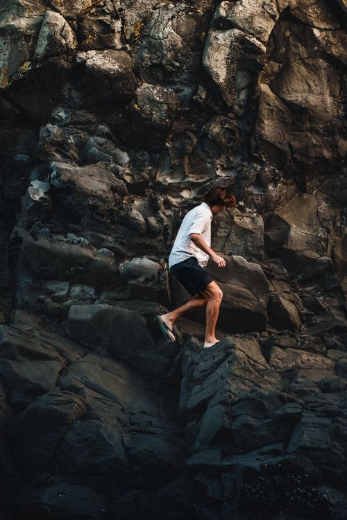 Free Man exploring rugged rocky terrain in daylight, showcasing outdoor adventure and exploration. Stock Photo