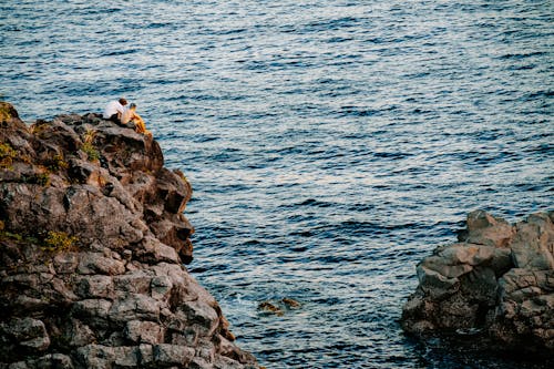 A couple is sitting on the edge of a cliff