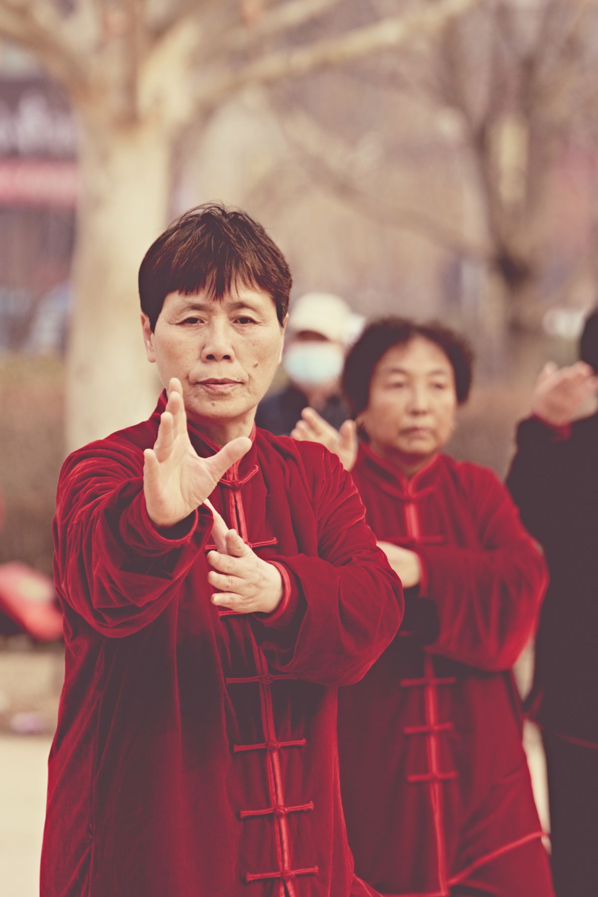 A group of people performing tai chi exercises outdoors in traditional red outfits