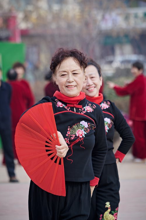 Two women in traditional chinese clothing holding red fans