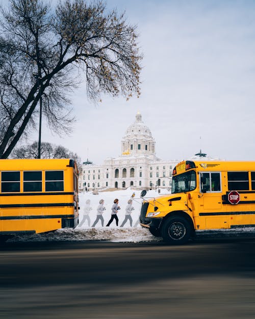 Two Yellow Buses Parked Near White Building