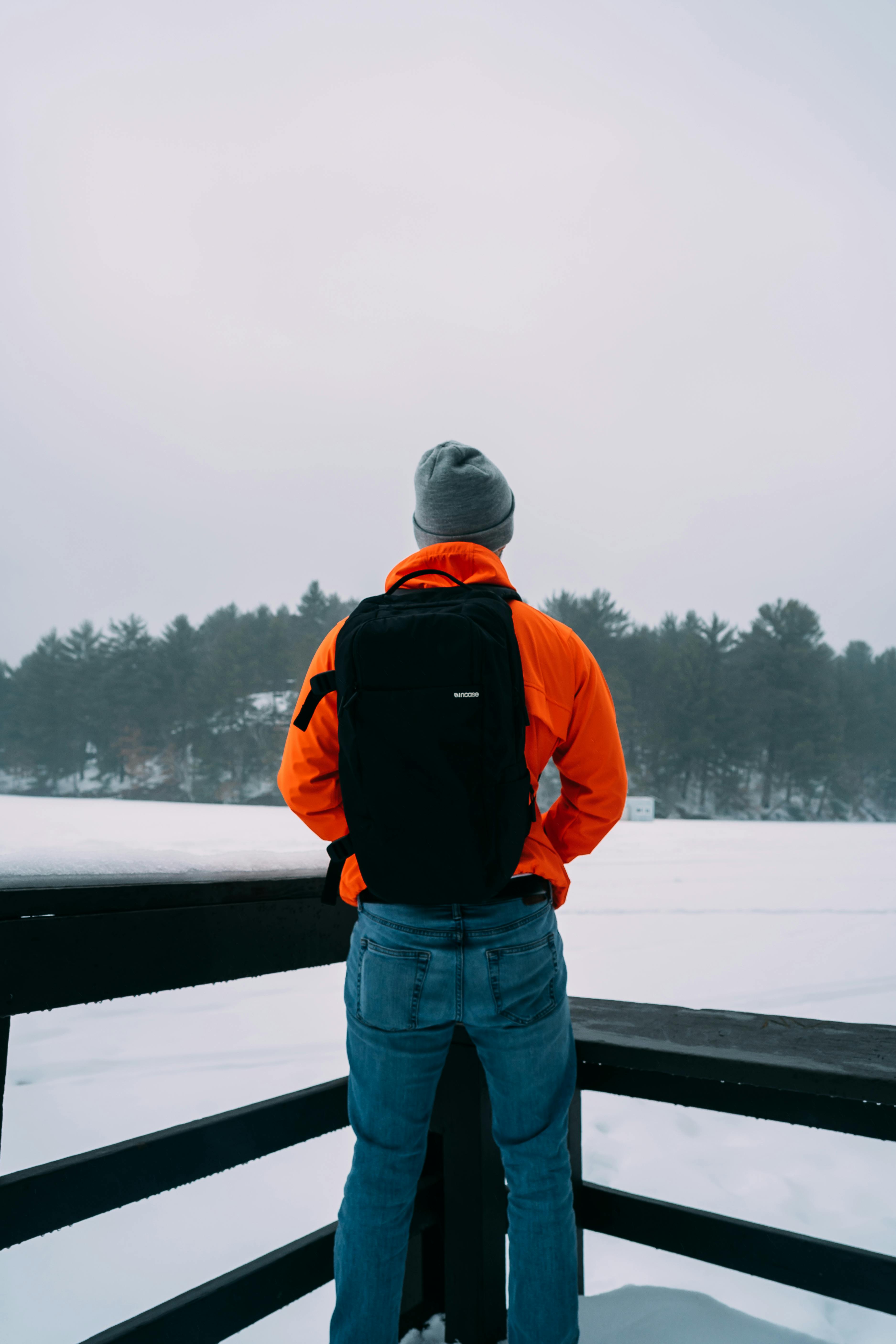 在威斯康星州白雪皑皑的湖边，一名身穿亮橙色夹克的男子站在松树环绕之中