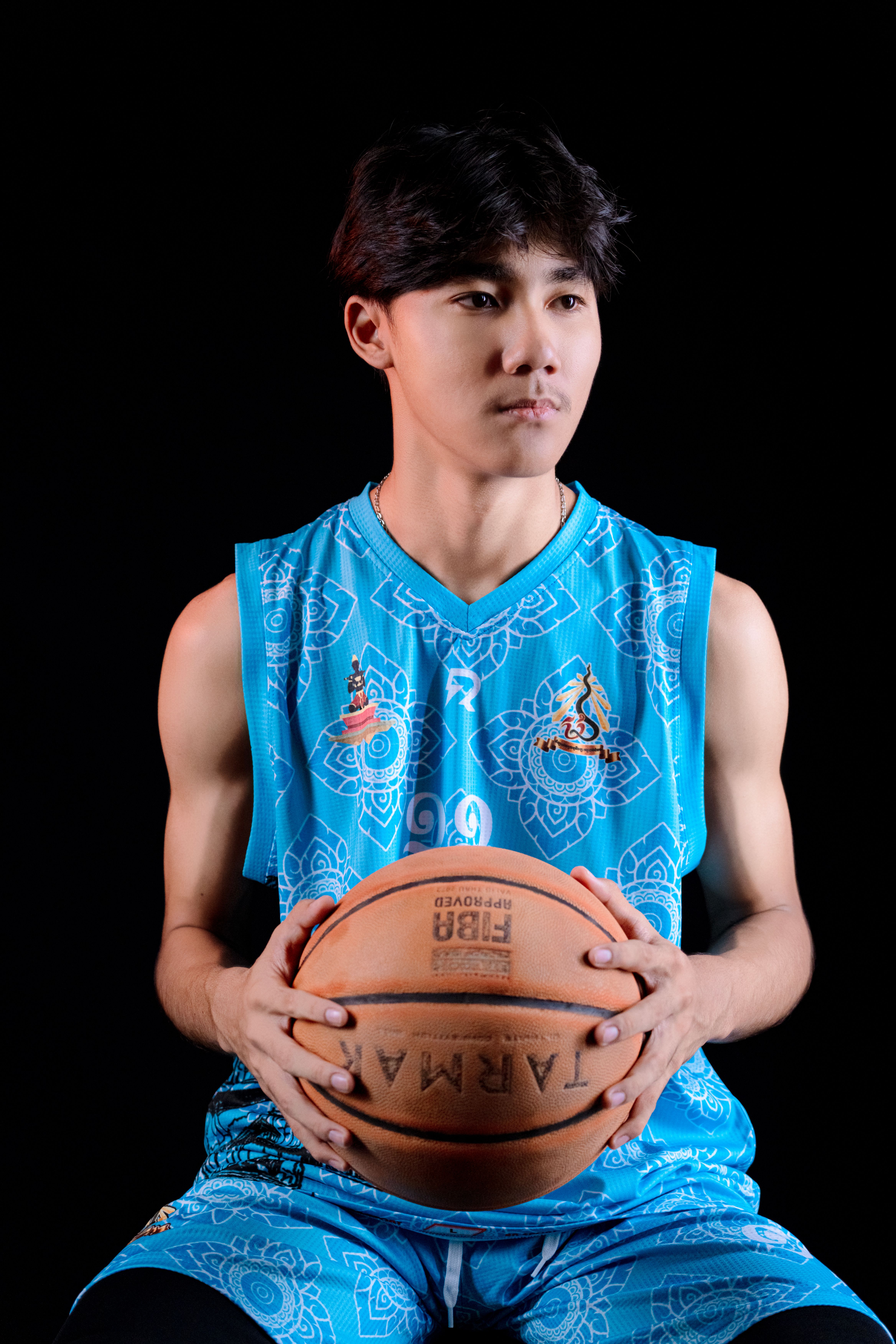 Portrait of a young male basketball player in vibrant sportswear holding a basketball.