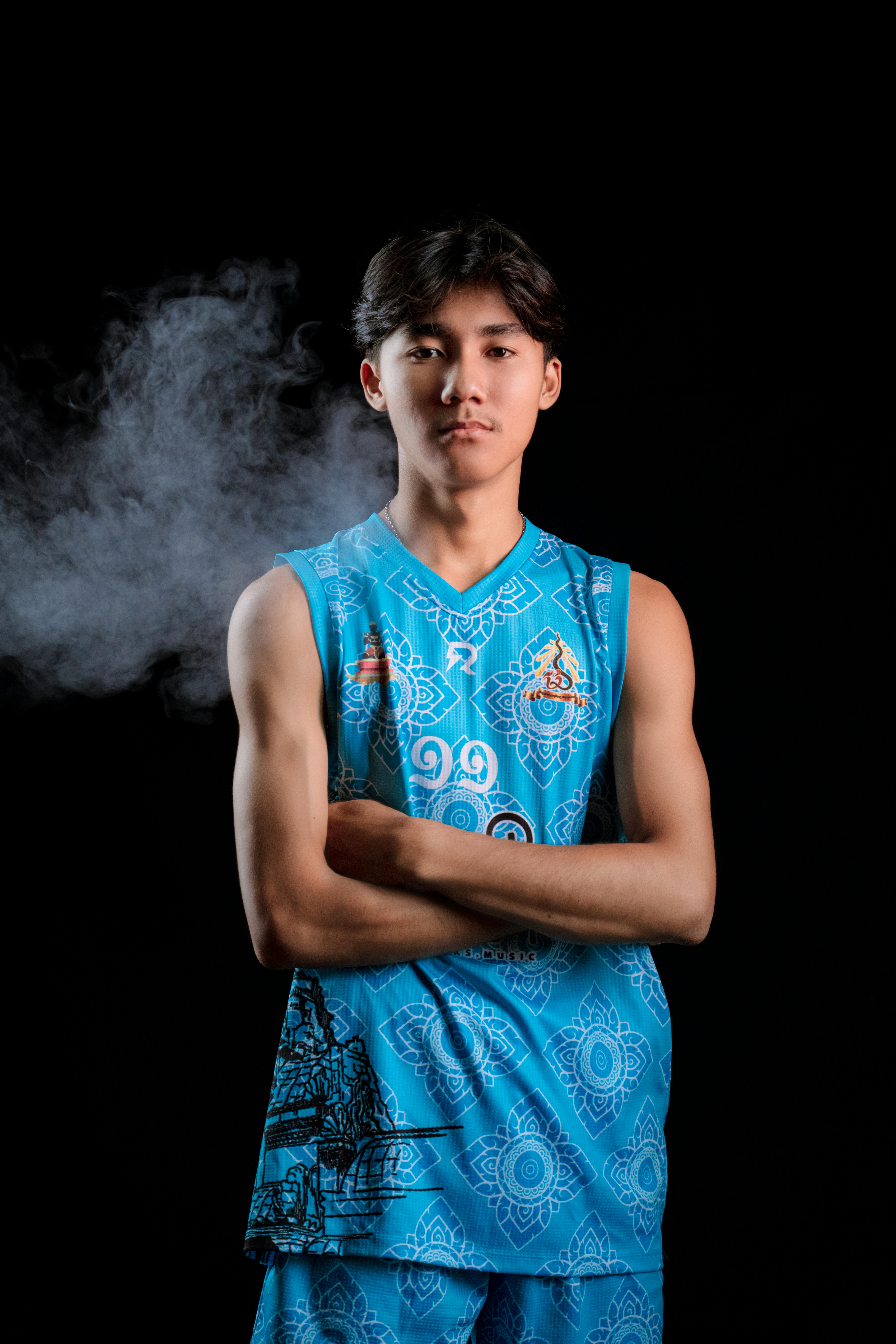 Confident young basketball player posing in blue sportswear in a studio.