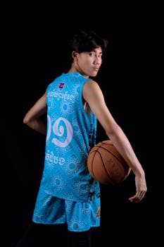 Portrait of a young adult male basketball player posing with a ball in sportswear.