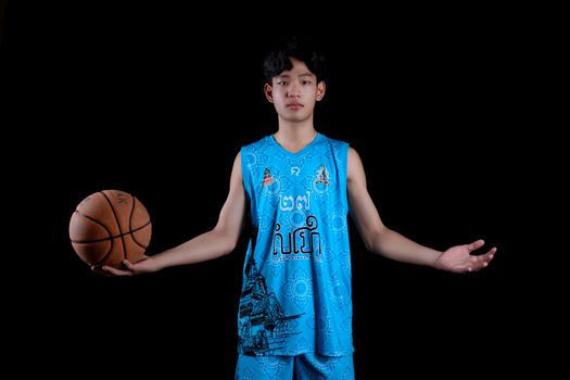 Young basketball player in vibrant blue uniform posing confidently with a basketball in a studio setting.