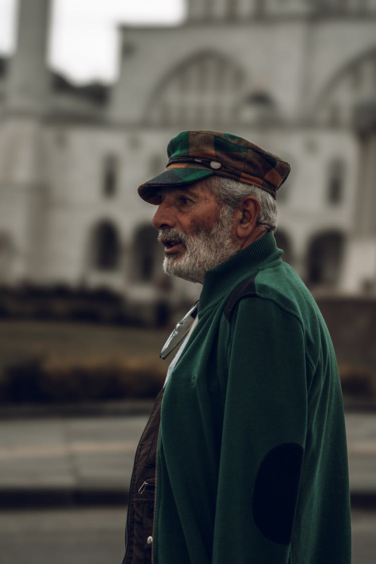 Profile Of A Senior Man Wearing A Hat, Against A Mosque