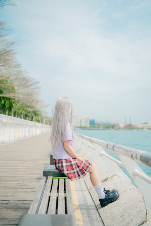 Woman with White, Dyed Hair Sitting on Bench on Promenade on Sea Shore