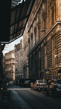A scenic street view showcasing vintage buildings and parked cars under warm sunlight.