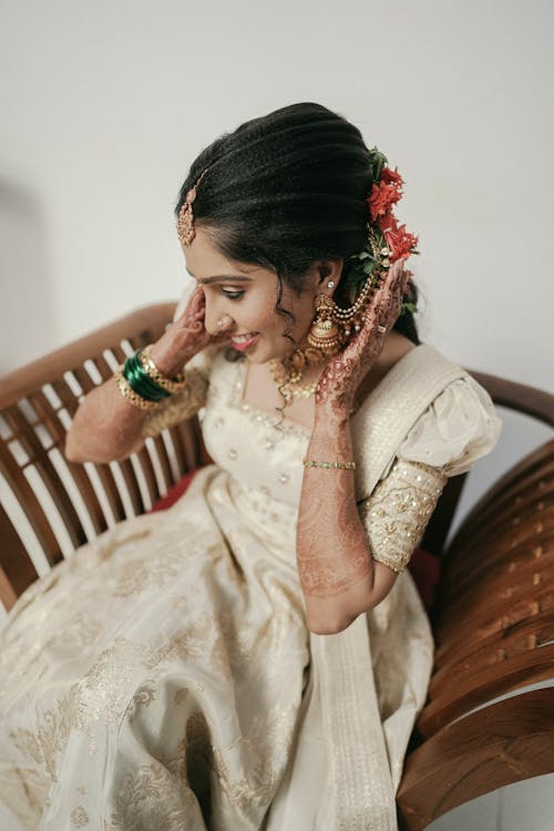A bride in traditional indian attire sitting on a chair