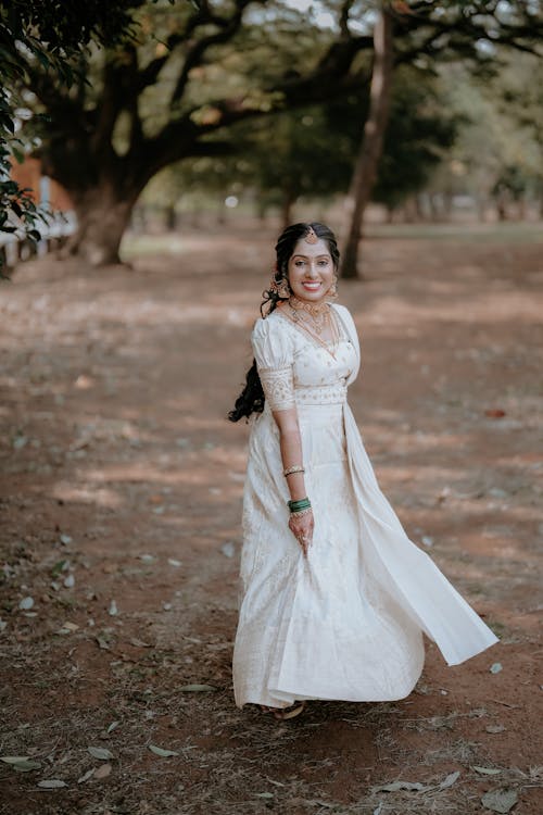 A woman in a white dress walking through a park