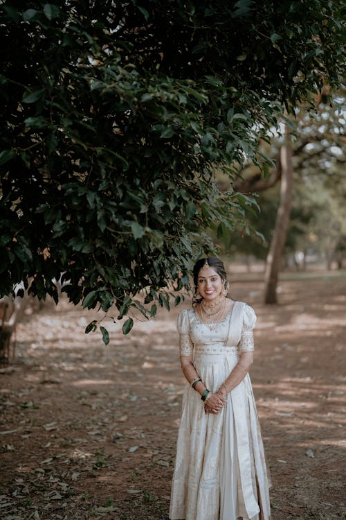 A woman in a white dress standing in front of trees