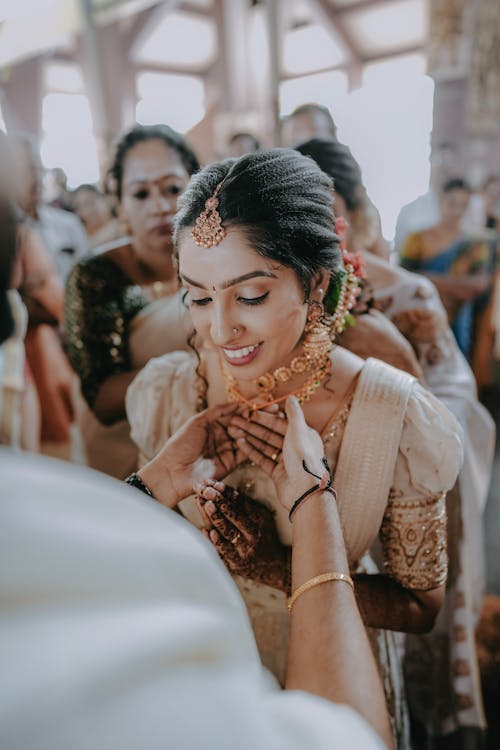A bride putting on her necklace at her wedding