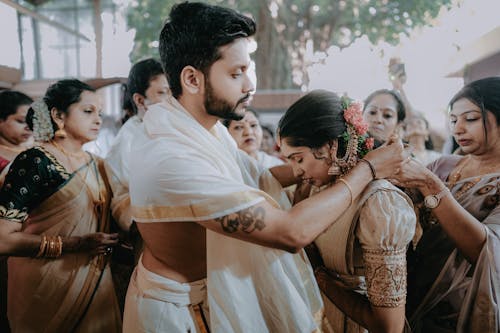 A man in white sari is hugging a woman in a traditional indian wedding
