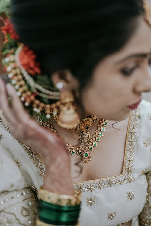 A bride in traditional indian attire with a necklace and earrings