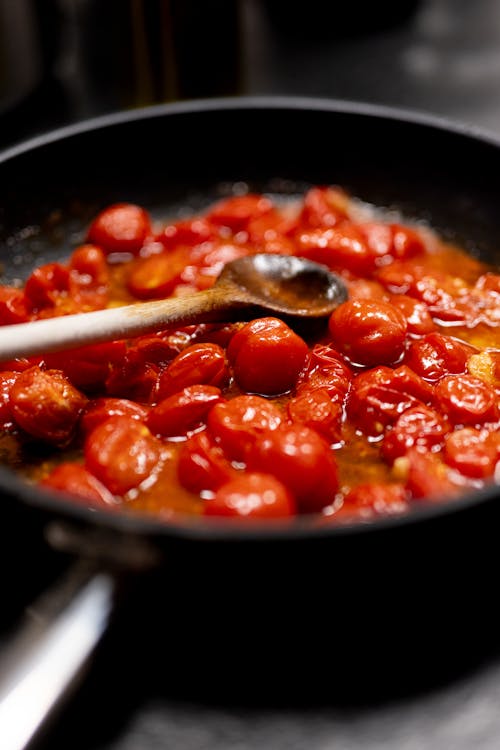 A pan with tomatoes and a spoon in it