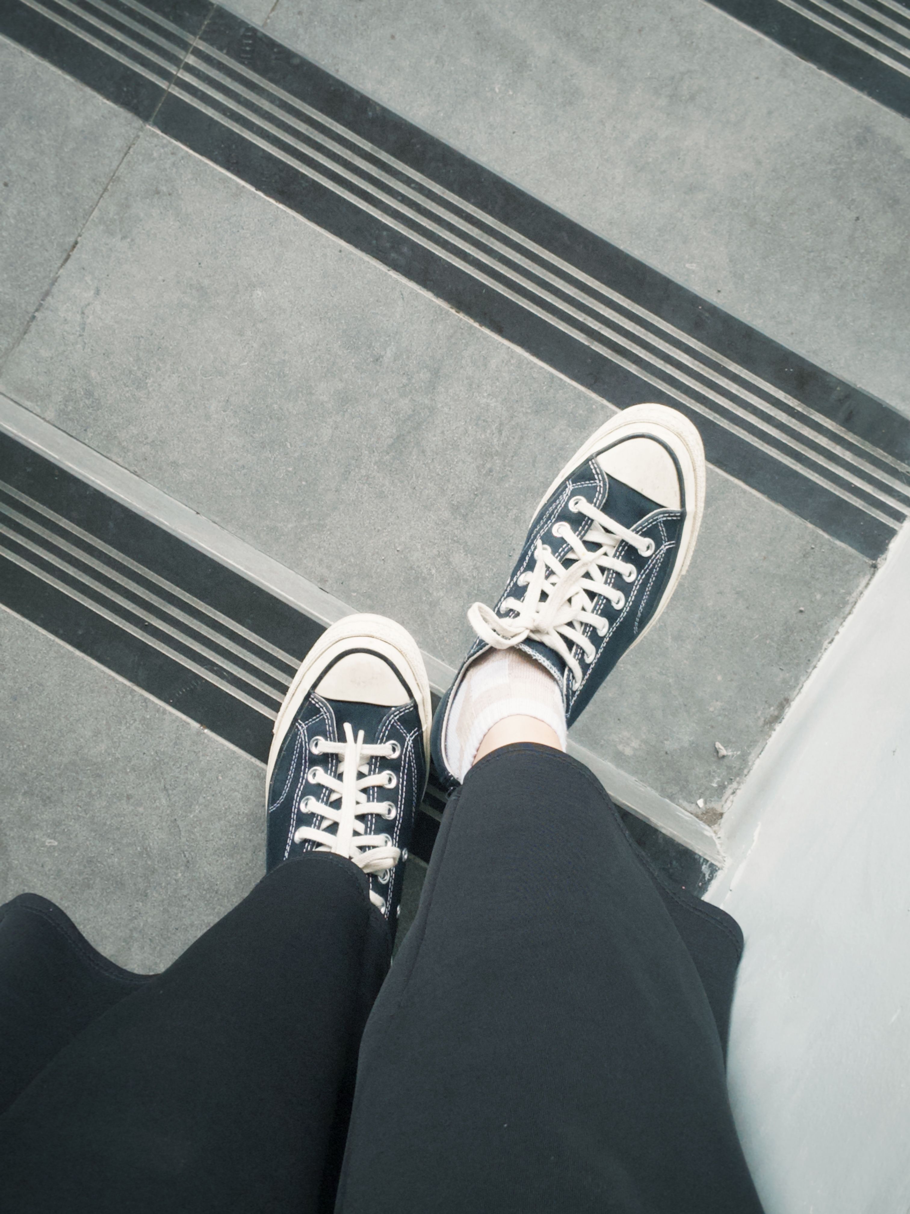 A top view of stylish sneakers standing on urban concrete stairs.