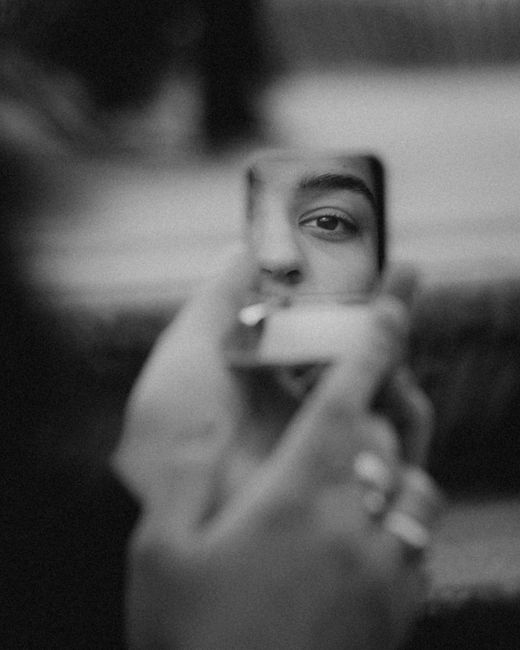 Black and white image of a woman's eye reflected in a small mirror, conveying introspection.