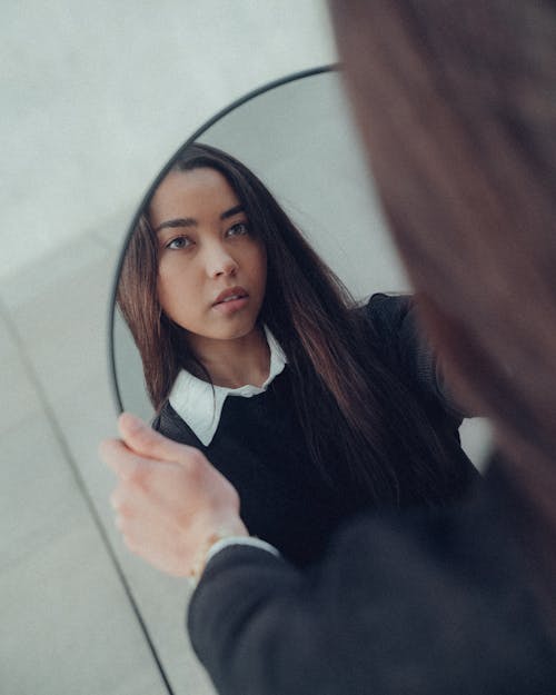 Brunette Woman Looking at Reflection in Mirror