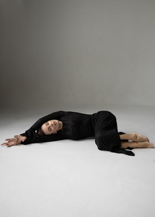 Studio Shot of a Woman in a Black Dress Lying on the Floor 