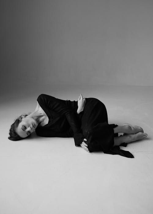 Studio Shot of a Woman in a Black Dress Lying on the Floor 