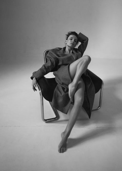 Studio Shot of a Woman in a Coat Sitting on a Chair 