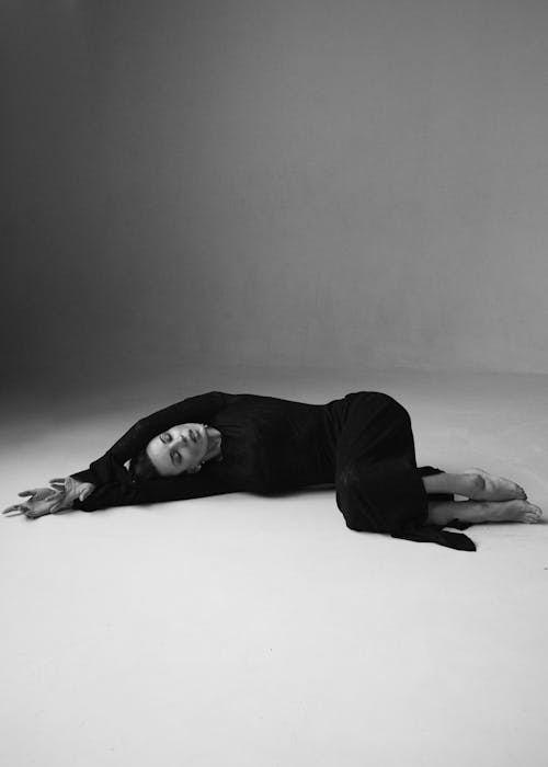 Studio Shot of a Woman in a Black Dress Lying on the Floor 