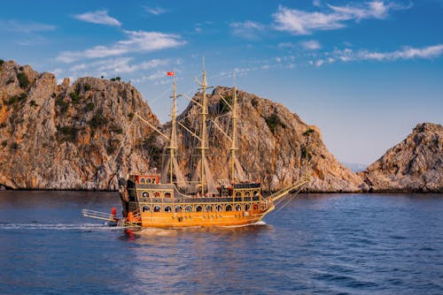 A ship sailing in the ocean near a rocky shore