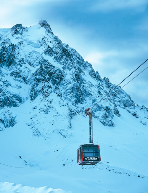 A cable car is traveling up a snowy mountain