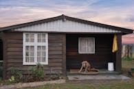 日落时分，迷人的乡村小屋门廊上，一只忠诚的狗正在休息