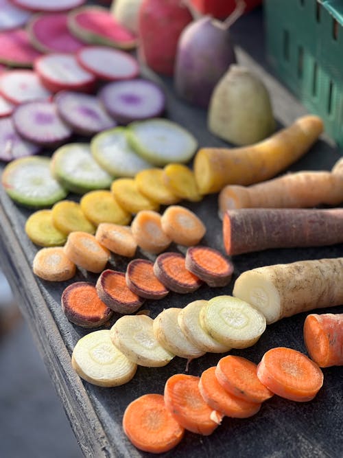 A table with different colored carrots and radishes