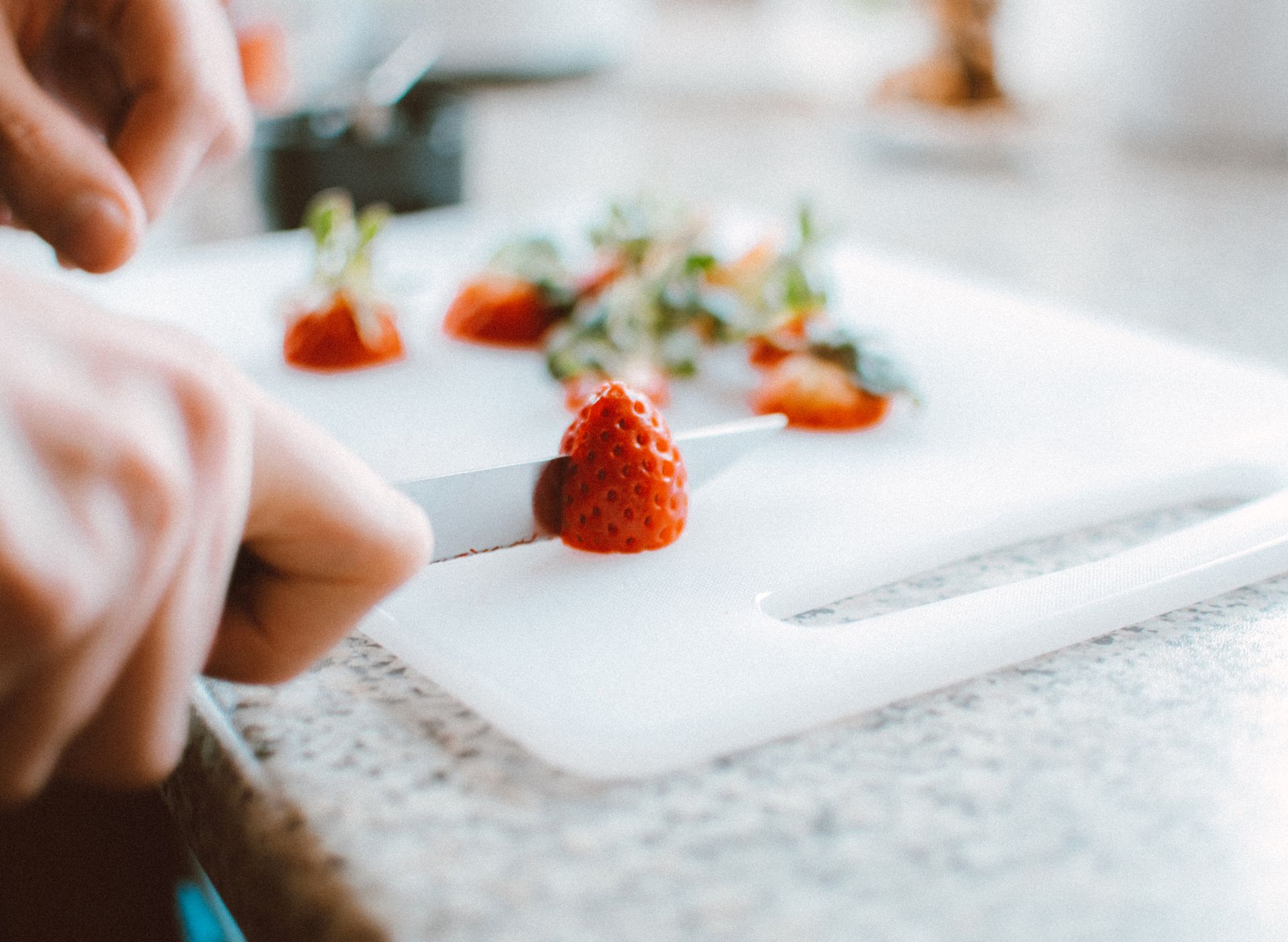 Close-up of fresh strawberries being sliced on a chopping board, perfect for food and kitchen stock images.