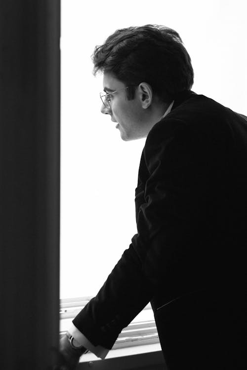 A man in a suit looking out a window