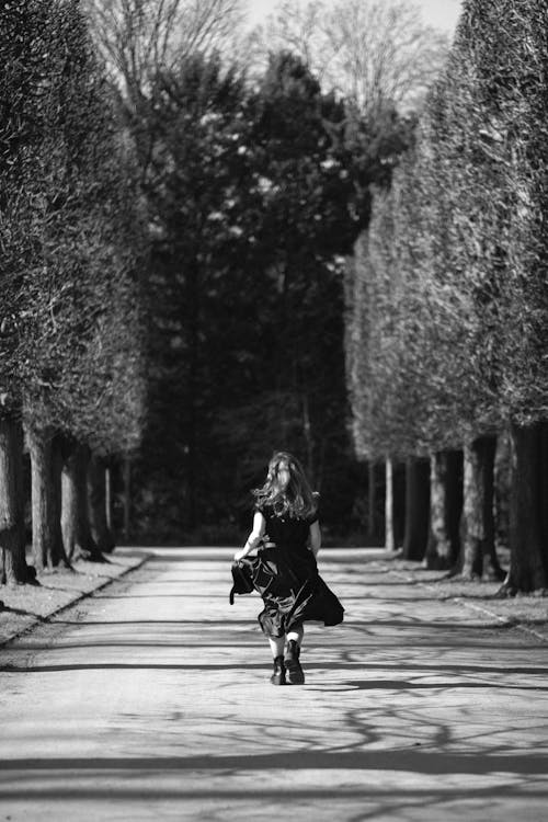 Back View of Woman in Dress Walking at Park in Black and White