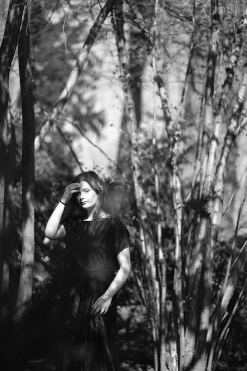A black and white photo of a woman standing in the woods