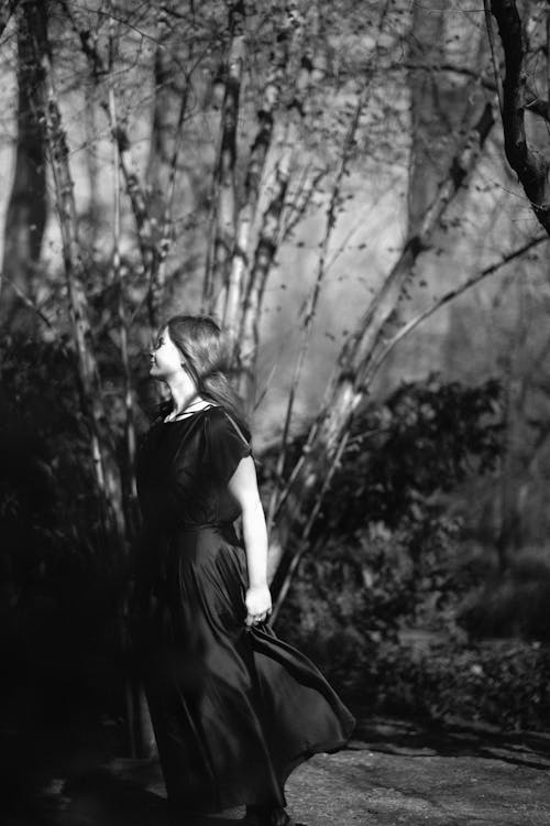 Woman in Dress Standing near Tree in Black and White