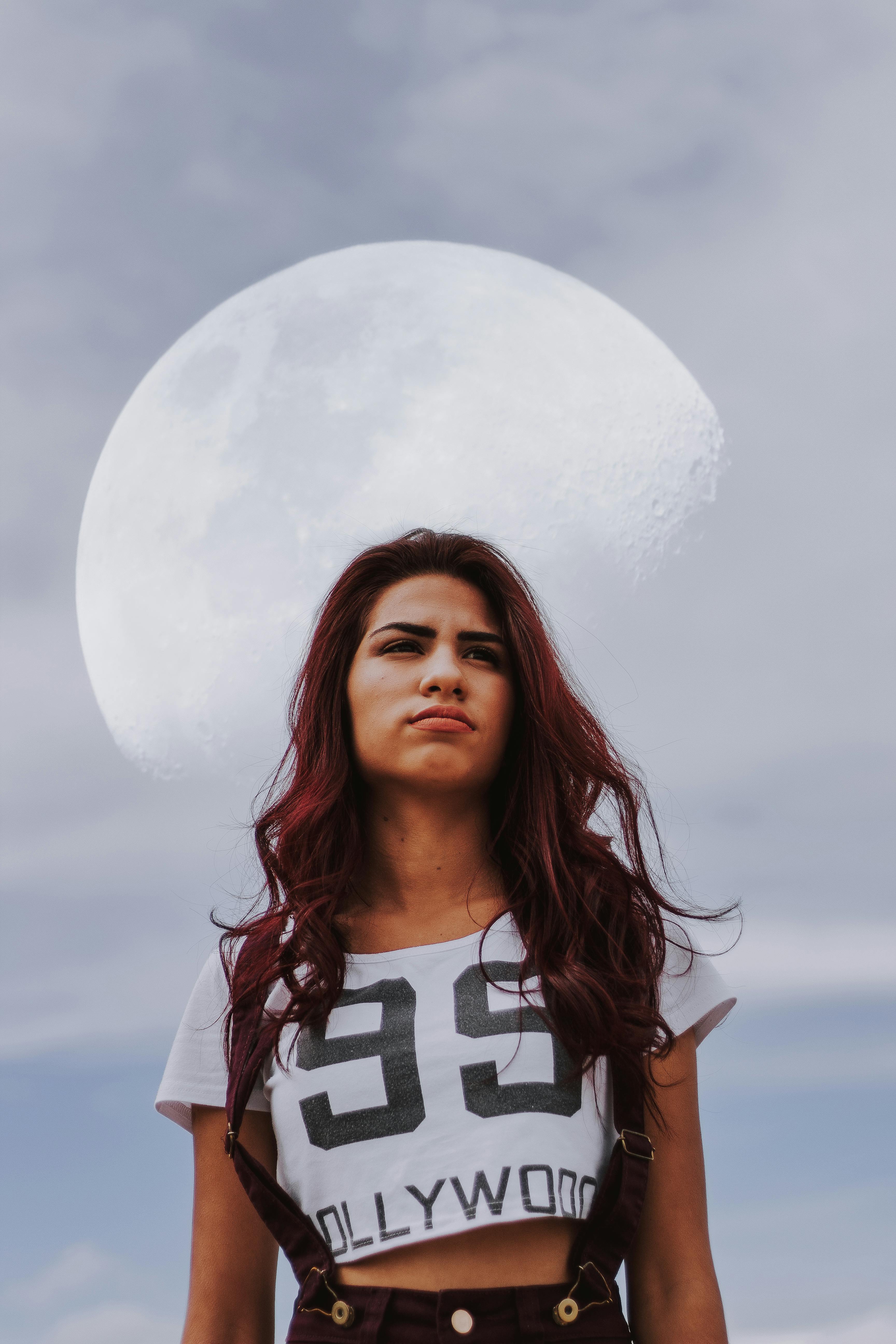 一位女子的梦幻肖像，蓝天上她身后月亮若隐若现