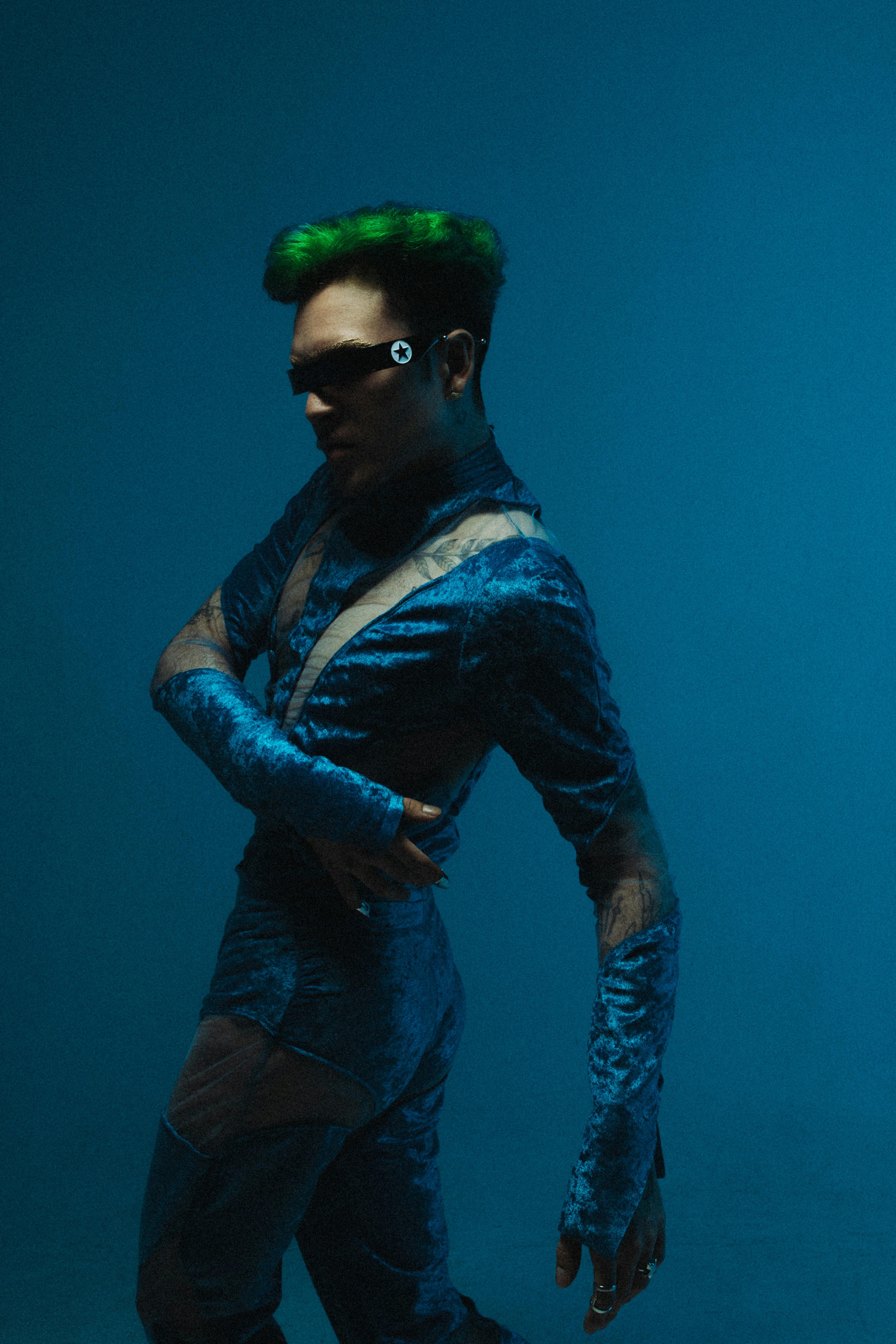 modern studio shot of a model with green hair wearing a blue costume