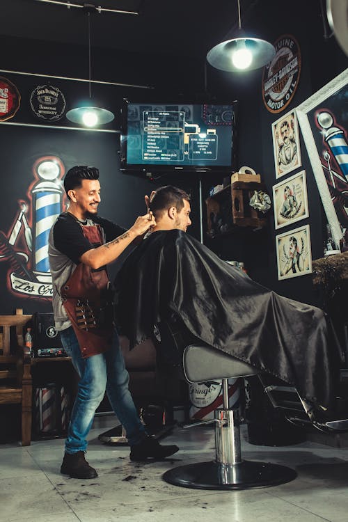 Free Smiling Man Cutting Another Mans Hair Inside Shop Stock Photo
