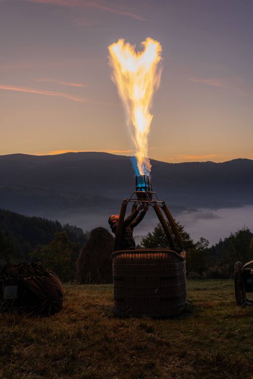 Free A hot air balloon being prepared at dawn in the mountains of Romania, with flames illuminating the scene. Stock Photo