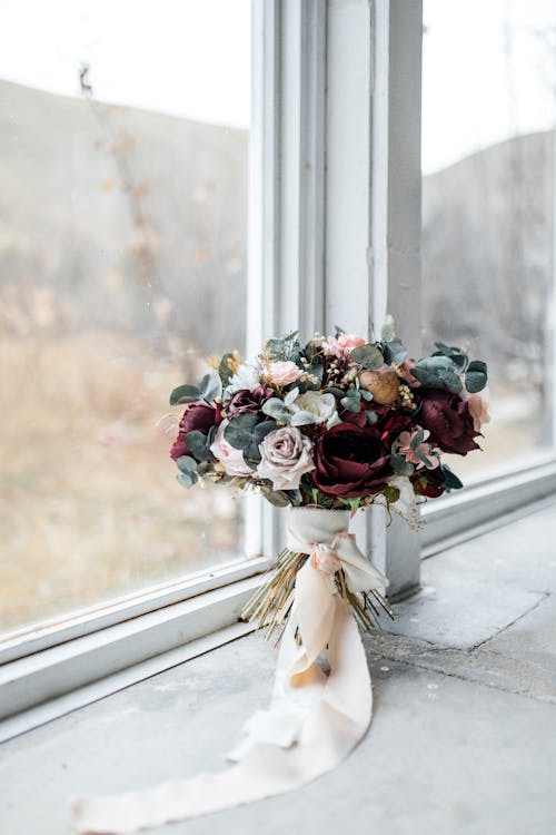 A bouquet of flowers sitting on a window sill