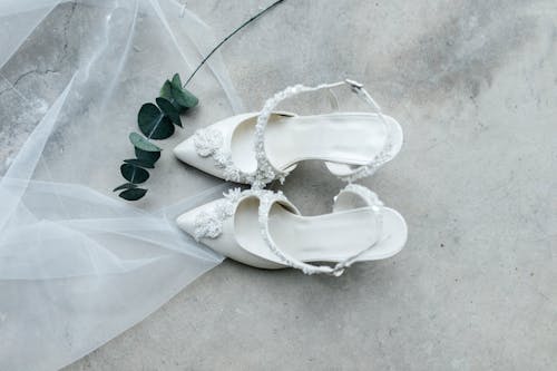 A pair of white wedding shoes with a veil